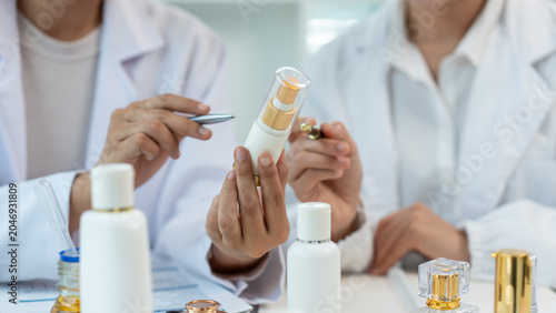 фотографія Lab professionals examine a skincare bottle and cosmetic samples in a bright laboratory, showing product testing, research, and beauty development