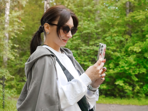 Stylish Woman With Sunglasses Using Smartphone in Green Park