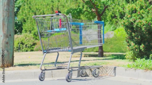 Empty metal shopping cart abandoned on asphalt cur