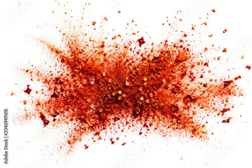 Red chili powder and flakes scatter on white background.