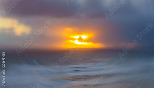 Canvas-taulu Impressionist coastal with setting sun through clouds on horizon with intentional camera movement swirl over sea at Ripiro Beach Northland New Zealand