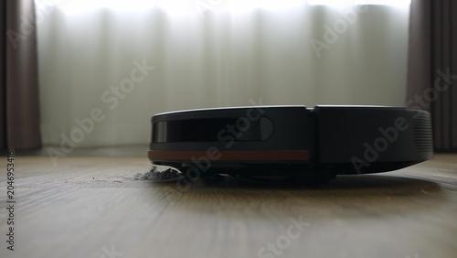 Foto A robotic vacuum cleaner glides across the floor, highlighting the growing role of automation and innovative technology as indispensable assistants in today’s smart homes