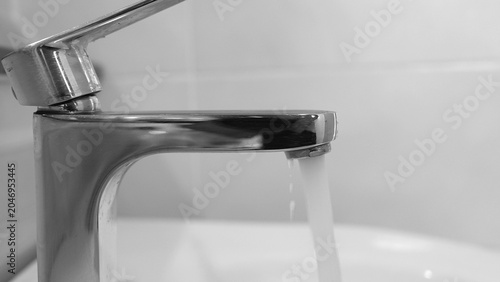 Fotografie A flowing faucet with no purpose illustrates unnecessary resource consumption, urging us to practice mindful water use, support sustainable living, and reduce the environmental impact at home