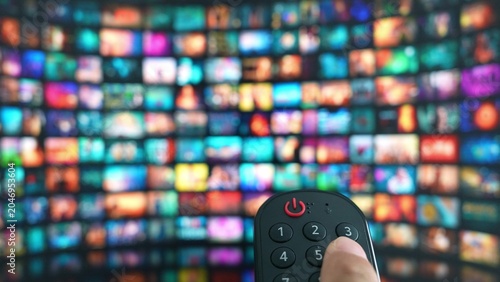 Obraz na płótnie A remote in hand, navigating endless entertainment on a giant TV reflects the ease of modern content selection, home theater experiences, technological advancement, and the joy of streaming media
