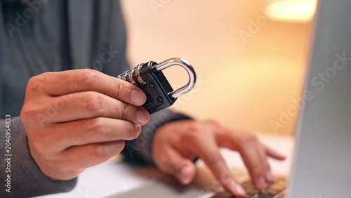 Фотография A hacker examines a padlock, symbolizing an attempt to crack security codes
