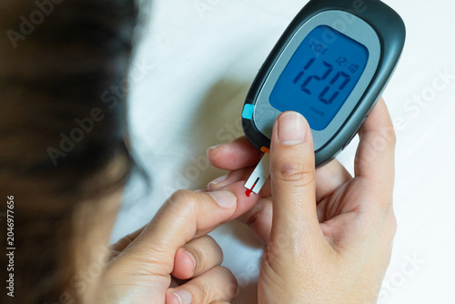 Foto Woman's hands checking diabetes and hyperglycemia with digital blood sugar meter