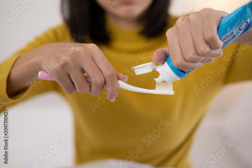 A close-up image of a young woman brushing her teeth after finishing a meal.