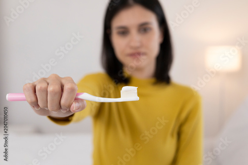 A close-up image of a young woman brushing her teeth after finishing a meal.