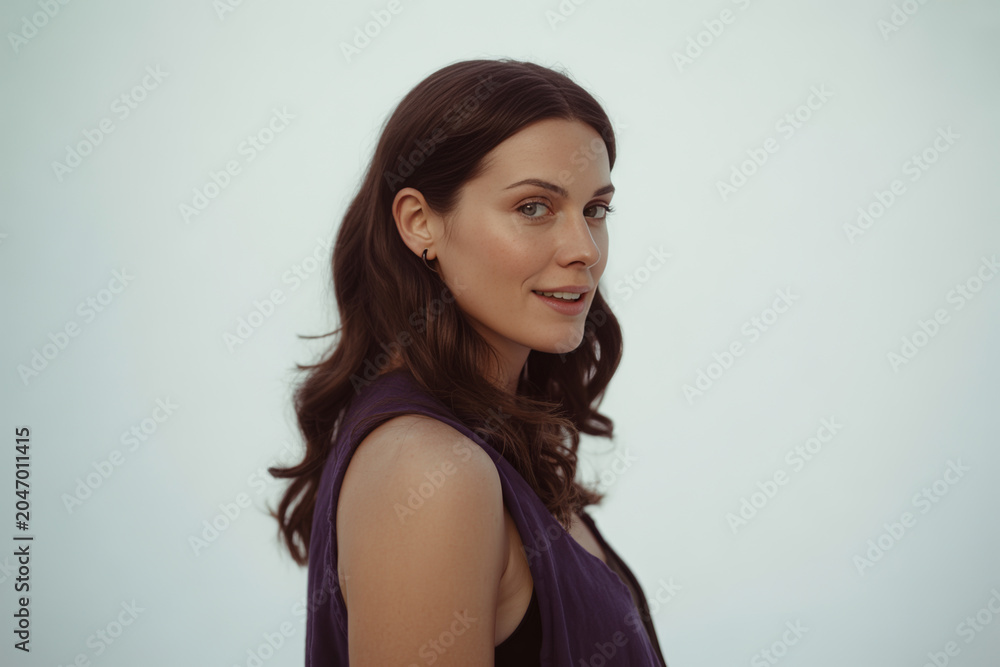 Fototapeta premium Portrait of a young woman with wavy hair looking over her shoulder, portrait