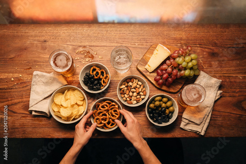 Hands sharing beer and many snacks for happy hour