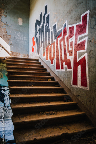 Graffiti-covered staircase inside the abandoned Savane Sanatorium in Tskaltubo, Georgia, blending urban art with Soviet-era decay. The grafiti says 