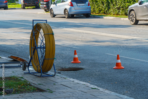 Fiber optic cable reel near open manhole on city street