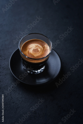 Coffee in glass cup on a dark stone background. Soft focus. Close up. Copy space.