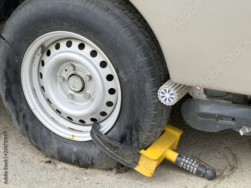 View of a yellow wheel clamp security lock attached to a vehicle tire with a motor mover roller in Sariyer, Istanbul, Turkiye.