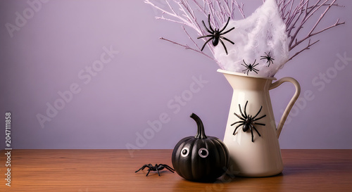 Halloween decoration with black spiders pumpkins and branches in a white pitcher