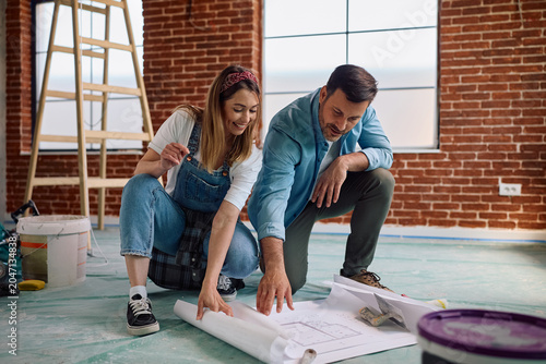 Fotografie Happy couple examining renovation plans in their new home.