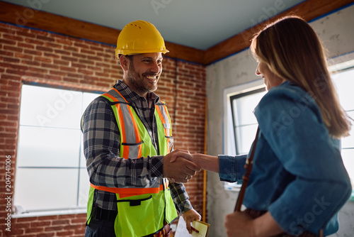 Obraz na plátně Happy construction worker and female homeowner shaking hands on site