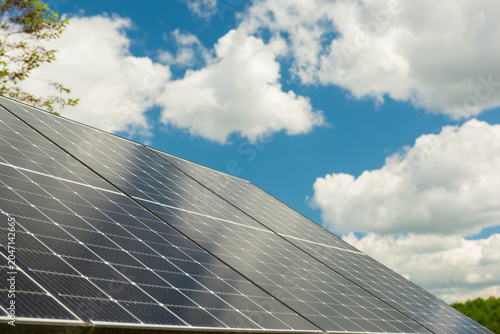 Solar panels on a rooftop under a bright blue sky with fluffy white clouds