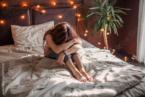 Photos Sad young woman lying in bed