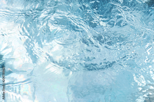 Water droplets create ripples on a clear surface during a sunny day at the swimming pool