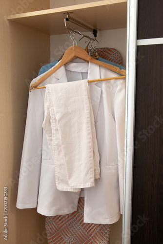 Foto Elegant white women pantsuit with double breasted blazer and trousers hanging on