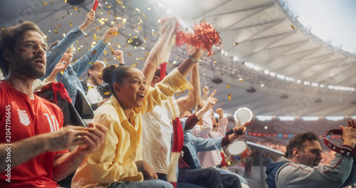 Εκτύπωση καμβά Diverse Men and Women in Stadium Seats Roar With Relieved Joy After a Decisive Soccer Championship Moment, as a Woman Lifts a Red Pompom, Fans Beat Tambourines and Gold Confetti Swirls Above