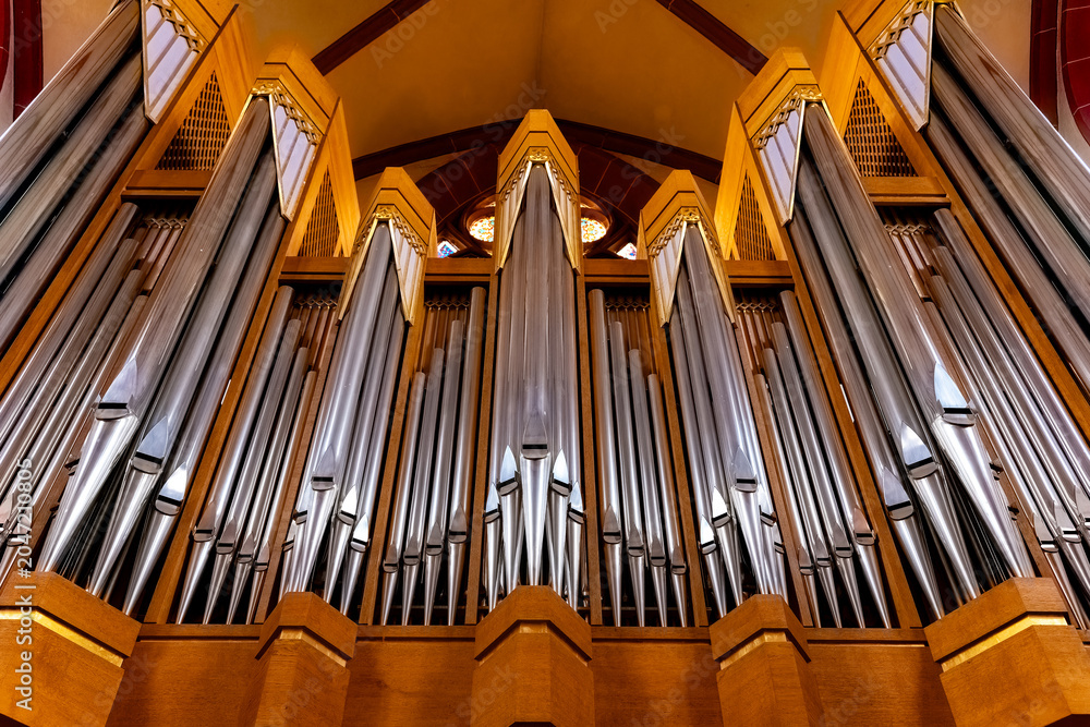Obraz premium Majestic organ pipes rise toward the ceiling in a breathtaking cathedral setting during a serene afternoon service