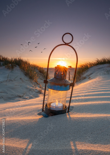 romantic lantern with candle on the beach in sunset light
