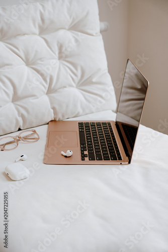 Laptop on White Bed with Accessories