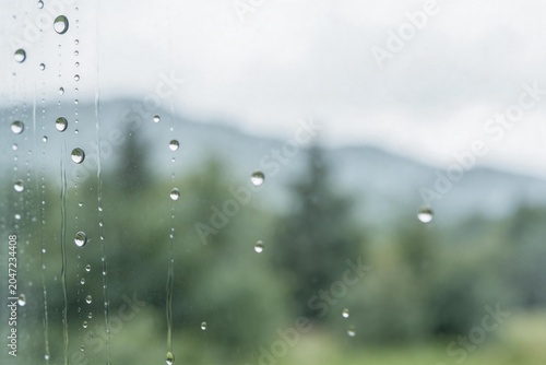 Raindrops on glass with blurred greenery