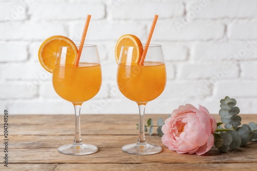 Two orange drinks with garnish on wooden table