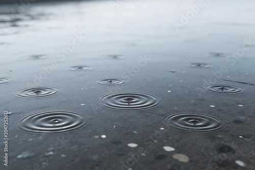 Raindrops creating ripples on wet surface