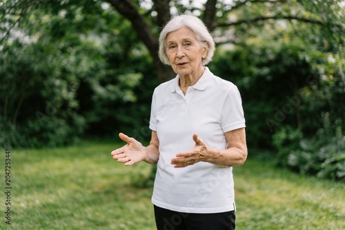 Elderly woman gesturing in garden