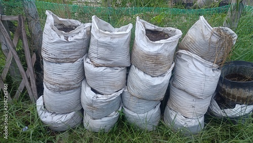 Stacked White Grow Bags Filled With Soil Outdoors In Grassy Area