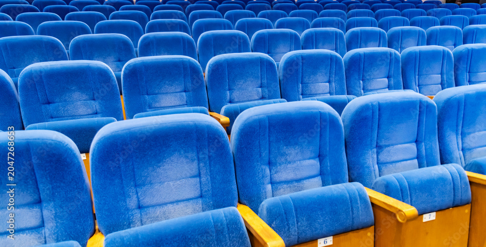 Naklejka premium Rows of empty blue velvet seat in theater. Concept of social distancing and waiting for event start.