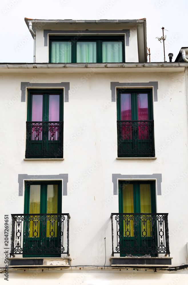 Obraz premium Whitewashed facade with balconies with colorful curtains in Tapia de Casariego town, Asturias