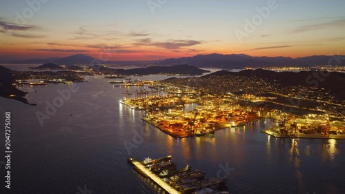 Breathtaking aerial footage capturing the port of piraeus in athens, greece, brilliantly illuminated against a spectacular twilight sky, showcasing the bustling global trade hub