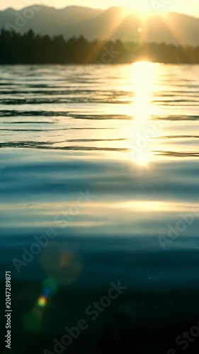 Golden sun setting over calm lake water ripples.
