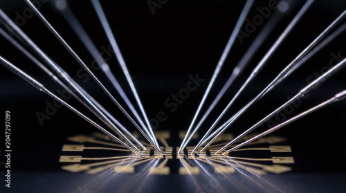 Macro view of microscopic probe needles contacting electrical pads on a semiconductor microchip during wafer testing