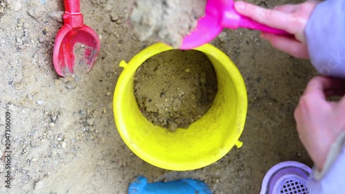 Join this captivating moment as tiny hands scoop sand from the sandbox and pour it into a bucket. Each grain contributes to their imaginative universe, filled with laughter and delight. 4k footage.