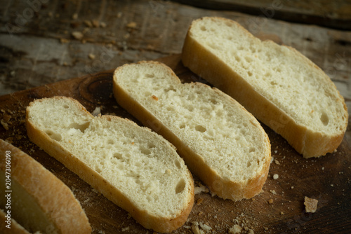 Slices of rustic ciabatta bread on wooden cutting board. Fresh pastry.