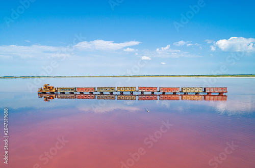 Tableau sur toile Aerial view of an old train rides on the railway laid in the water through the salt lake