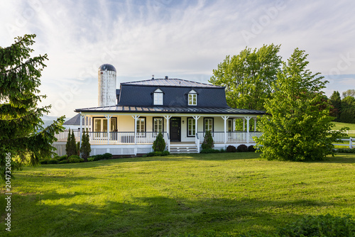 Foto Beautiful Second Empire style white country cottage with steeply-pitched black m