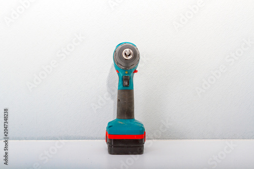 Cordless drill standing on white table. Power tool for home improvement and construction work. Handheld electric device for manual fixing, drilling and repair project renovation home DIY