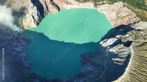 Aerial view of fog at Kawah Ijen volcano with turquoise sulfur water lake at sunrise.Amazing nature landscape view at East Java,Indonesia.Beautiful light Natural landscape background