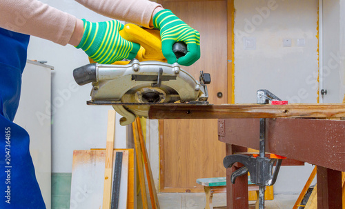 Foto Woman carpenter using circular saw to cut wooden board