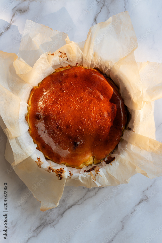 Fototapeta premium Whole homemade Basque burnt cheesecake in baking parchment paper.