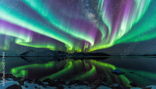 Bild auf Leinwand Vibrant aurora borealis display reflected on a calm arctic ocean at night