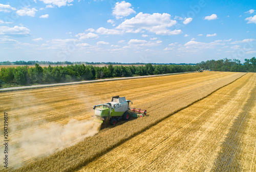 Foto Aerial view of combine harvester harvesting wheat in a field on a sunny day