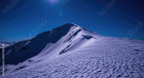 Dramatic snowy mountain peak under a dark blue sky.